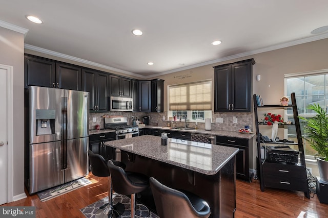 kitchen featuring light stone counters, appliances with stainless steel finishes, tasteful backsplash, a kitchen island, and dark hardwood / wood-style flooring