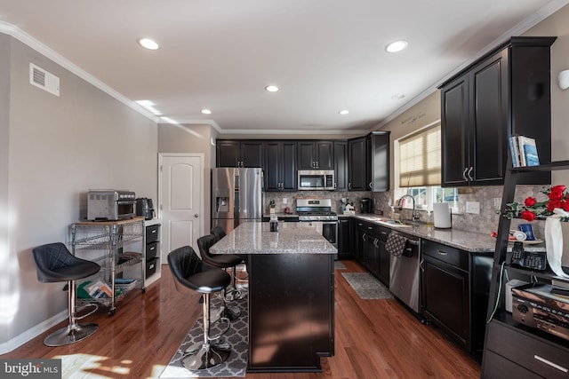 kitchen featuring a kitchen breakfast bar, dark wood-type flooring, a kitchen island, and stainless steel appliances