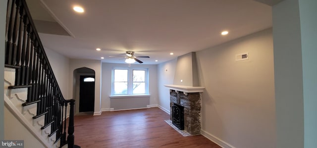 living room with dark wood-type flooring, a fireplace, and ceiling fan