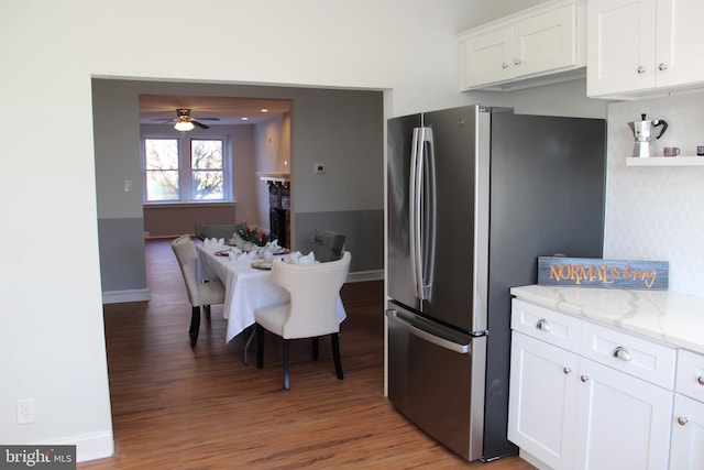 kitchen featuring hardwood / wood-style flooring, white cabinetry, light stone counters, and stainless steel refrigerator