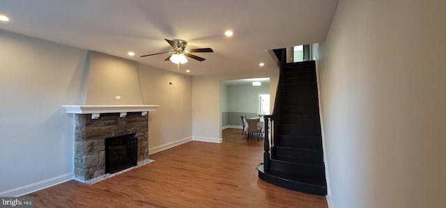 living room featuring a stone fireplace, ceiling fan, and hardwood / wood-style flooring