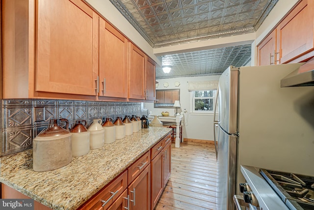 kitchen with light stone counters, stove, baseboards, light wood finished floors, and an ornate ceiling