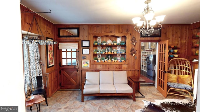 living area with washer / dryer, a notable chandelier, and wood walls