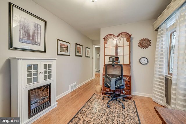 office featuring light wood-type flooring, visible vents, and baseboards