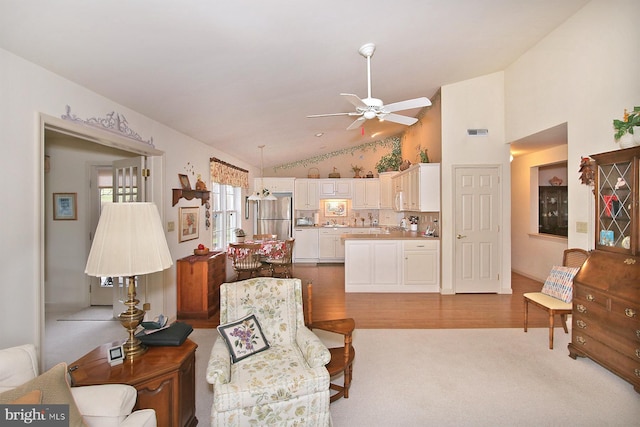 living room with light hardwood / wood-style floors, ceiling fan, and lofted ceiling