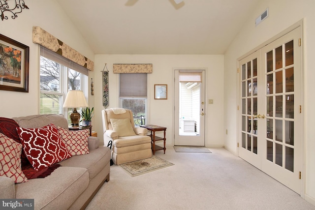 sitting room featuring french doors, light colored carpet, and vaulted ceiling