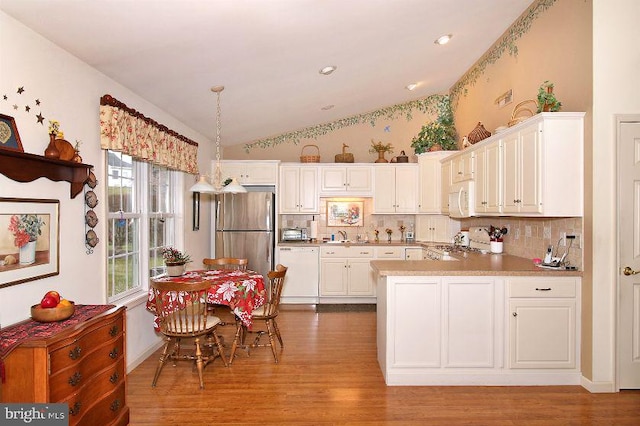 kitchen featuring white cabinetry, light hardwood / wood-style flooring, hanging light fixtures, and white appliances