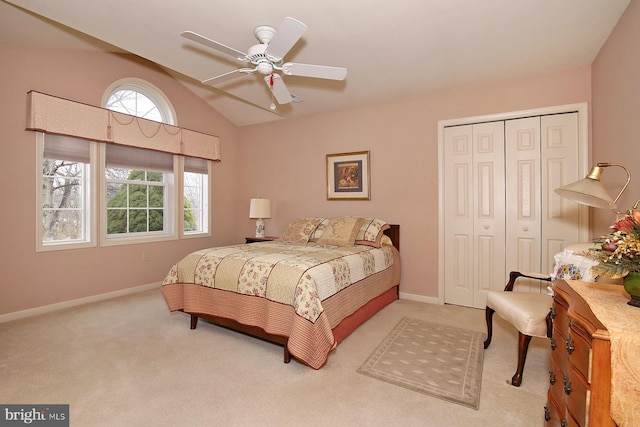 bedroom with a closet, light colored carpet, vaulted ceiling, and ceiling fan