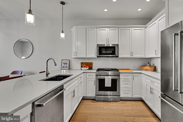 kitchen featuring white cabinets, sink, hanging light fixtures, kitchen peninsula, and stainless steel appliances