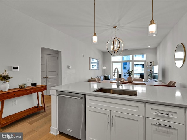 kitchen with light wood-type flooring, stainless steel dishwasher, sink, decorative light fixtures, and a notable chandelier