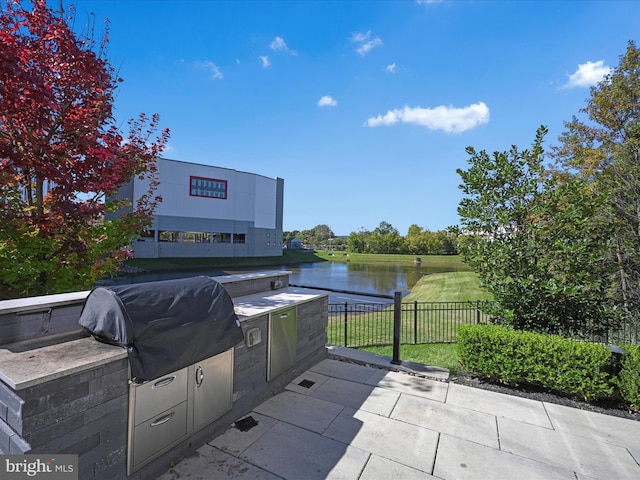 view of patio featuring an outdoor kitchen, a water view, and a grill