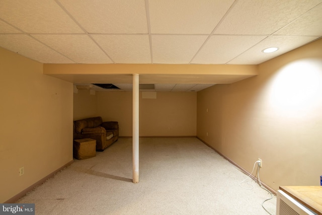 basement featuring a drop ceiling and light carpet