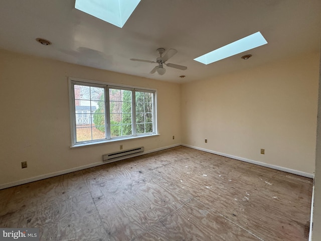 unfurnished room with ceiling fan, a skylight, and a baseboard heating unit