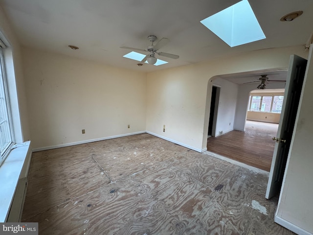 unfurnished room featuring a skylight, hardwood / wood-style flooring, and ceiling fan