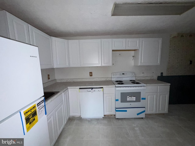 kitchen with light tile patterned floors, white cabinets, and white appliances