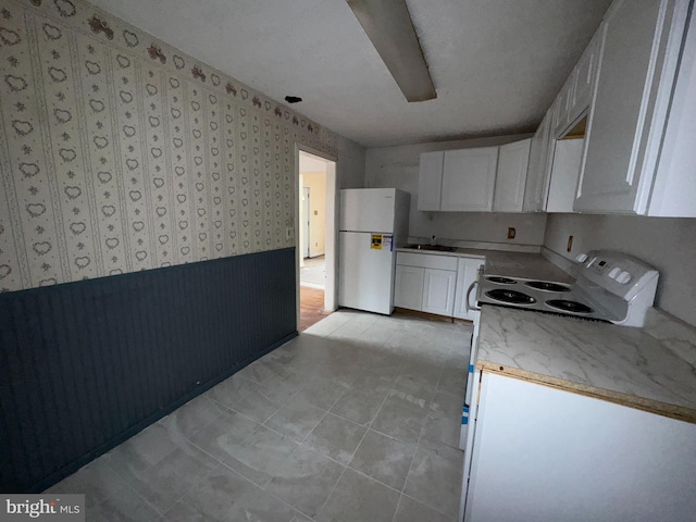 kitchen with white cabinetry, white appliances, sink, and light tile patterned floors