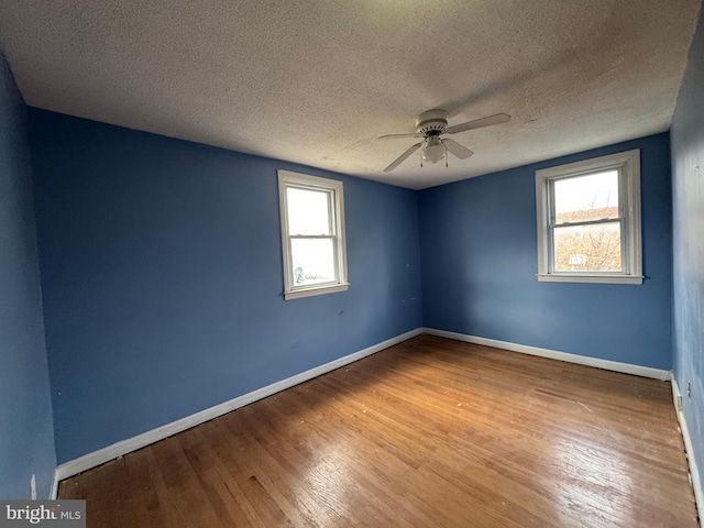 spare room with hardwood / wood-style floors, a textured ceiling, a wealth of natural light, and ceiling fan