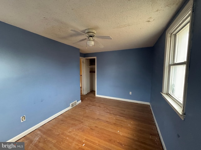 unfurnished bedroom with wood-type flooring, a textured ceiling, a closet, and ceiling fan