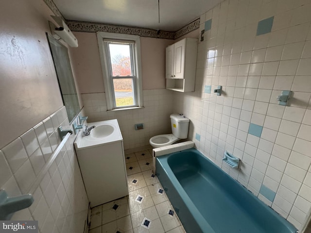 bathroom with vanity, tile walls, tile patterned flooring, toilet, and a bathing tub