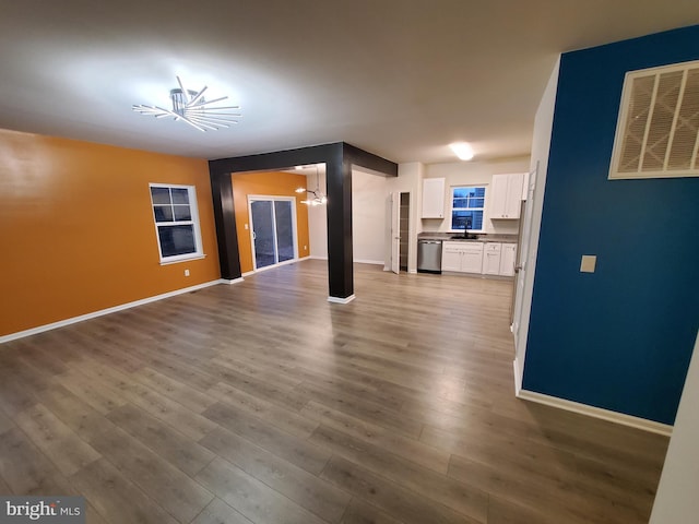 unfurnished living room with a notable chandelier, wood-type flooring, and sink