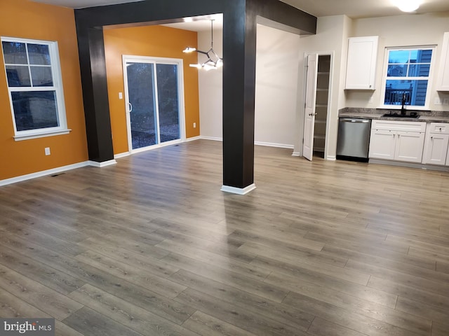 kitchen with stainless steel dishwasher, white cabinets, hanging light fixtures, and hardwood / wood-style flooring