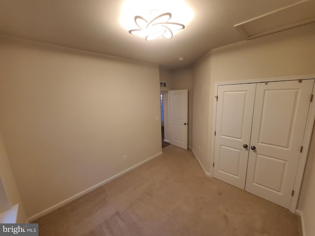 unfurnished bedroom with light carpet and a closet