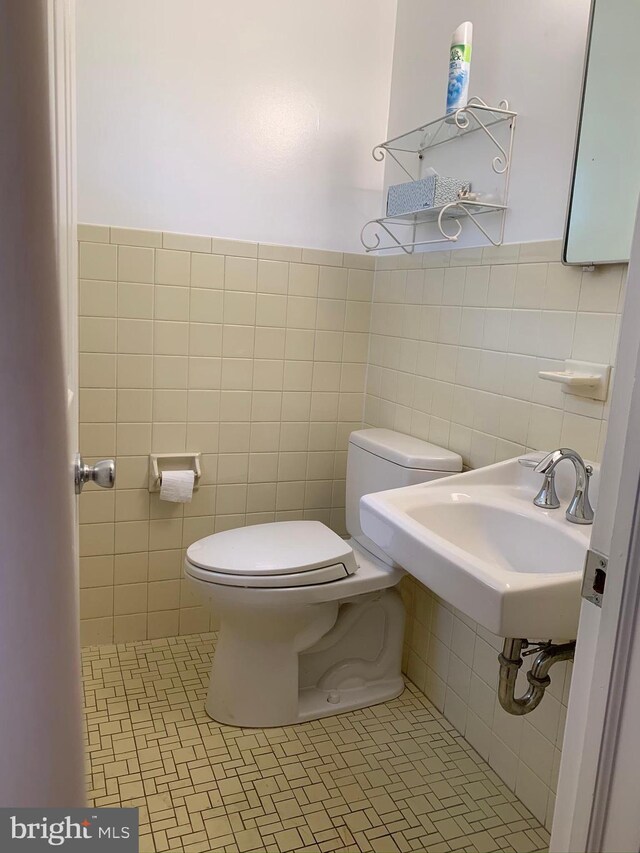 bathroom with tile patterned floors, tile walls, and toilet