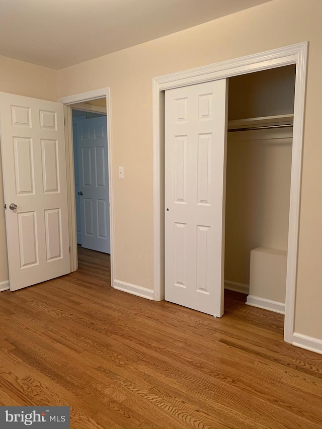 unfurnished bedroom with light wood-type flooring and a closet