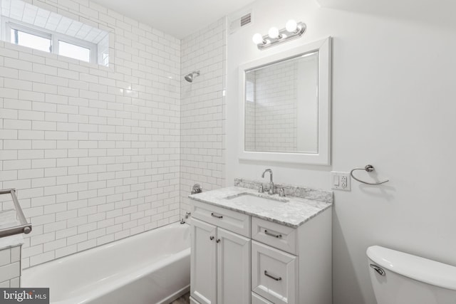 full bathroom with vanity, tiled shower / bath combo, and toilet