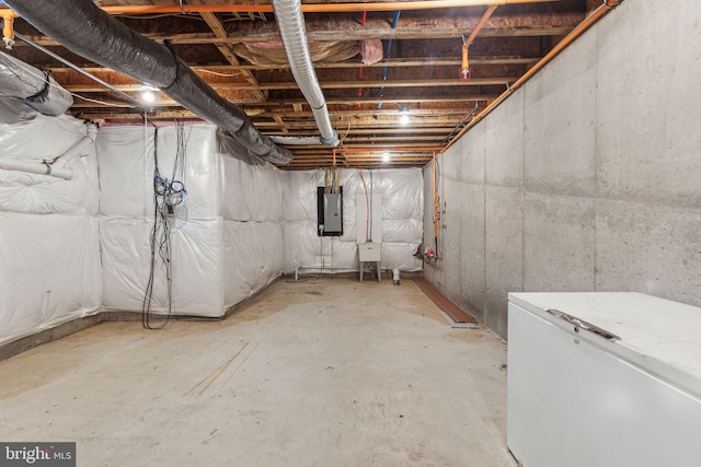 basement with electric panel and white fridge