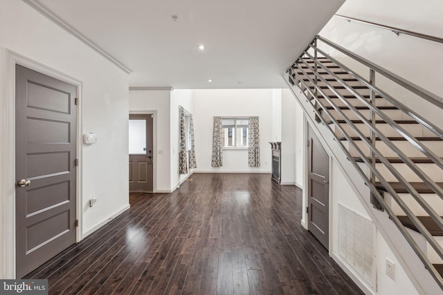 entryway with crown molding and dark wood-type flooring