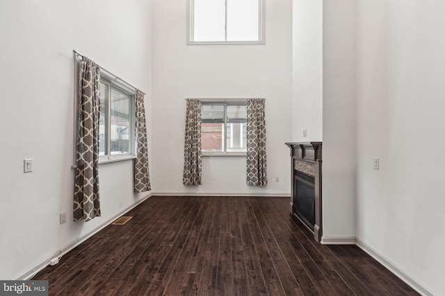 unfurnished living room with a towering ceiling and dark hardwood / wood-style floors