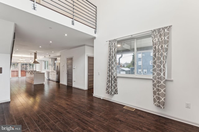 unfurnished living room with a towering ceiling and dark hardwood / wood-style flooring