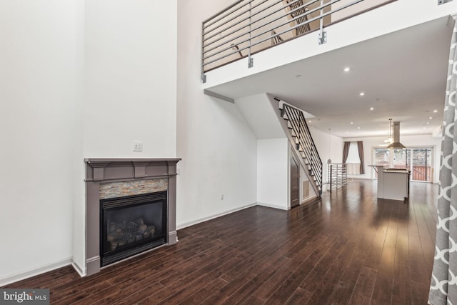 unfurnished living room featuring a high ceiling and dark wood-type flooring