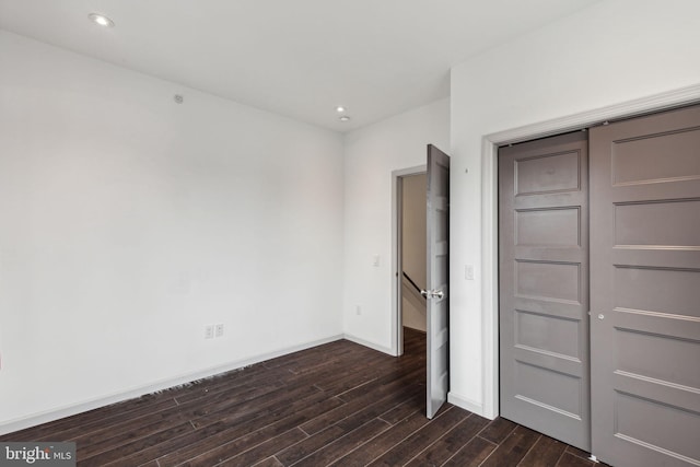 unfurnished bedroom featuring dark hardwood / wood-style flooring and a closet