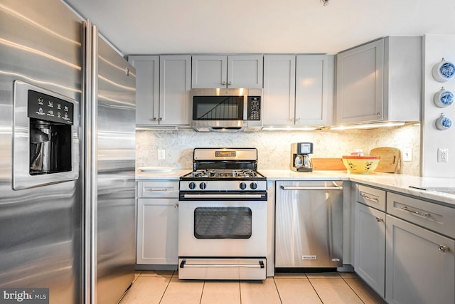 kitchen with stainless steel appliances, light tile patterned flooring, and gray cabinetry