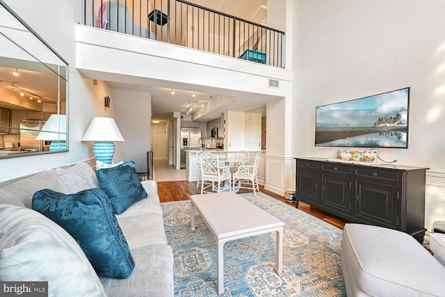 living room featuring hardwood / wood-style flooring, a high ceiling, and track lighting