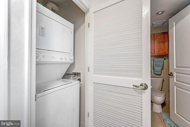 laundry room featuring light tile patterned flooring and stacked washer / dryer