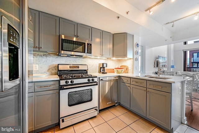 kitchen with sink, light tile patterned floors, gray cabinets, kitchen peninsula, and stainless steel appliances