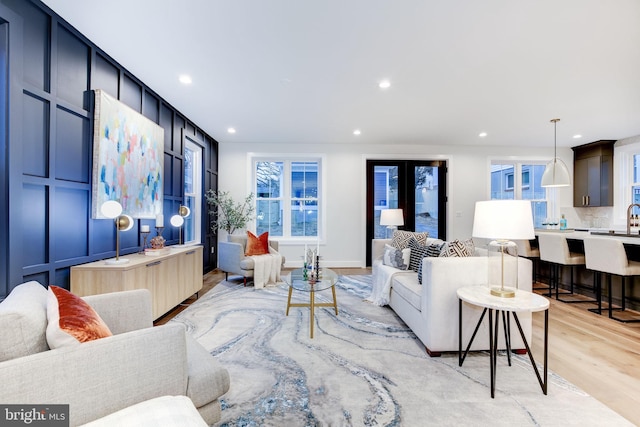 living room featuring light hardwood / wood-style floors, french doors, and a healthy amount of sunlight