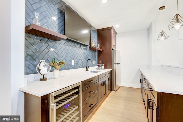 kitchen with pendant lighting, sink, stainless steel refrigerator, tasteful backsplash, and beverage cooler