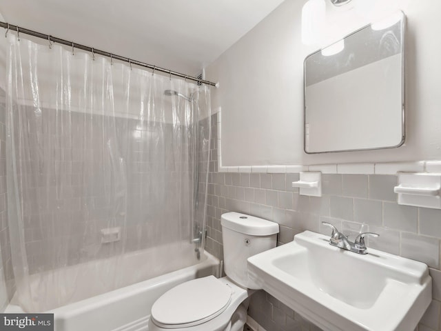 full bathroom featuring sink, shower / bathtub combination with curtain, tile walls, and toilet