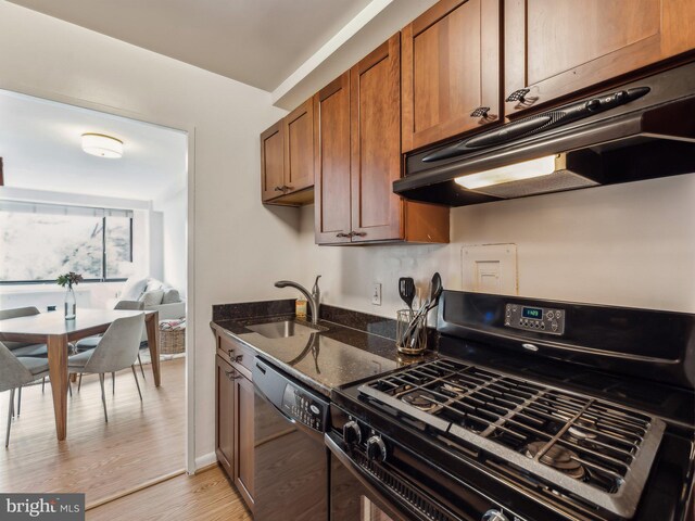 kitchen with dishwasher, sink, black range with gas cooktop, dark stone counters, and light wood-type flooring