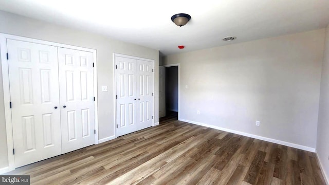 unfurnished bedroom featuring dark hardwood / wood-style floors and multiple closets