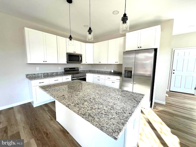 kitchen with white cabinetry, a center island, stainless steel appliances, and decorative light fixtures