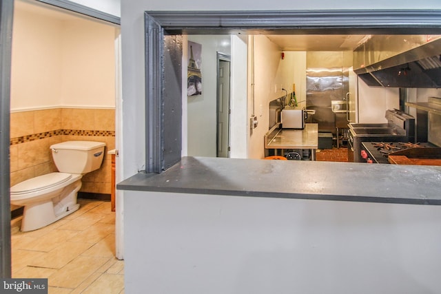 bathroom featuring toilet and tile walls