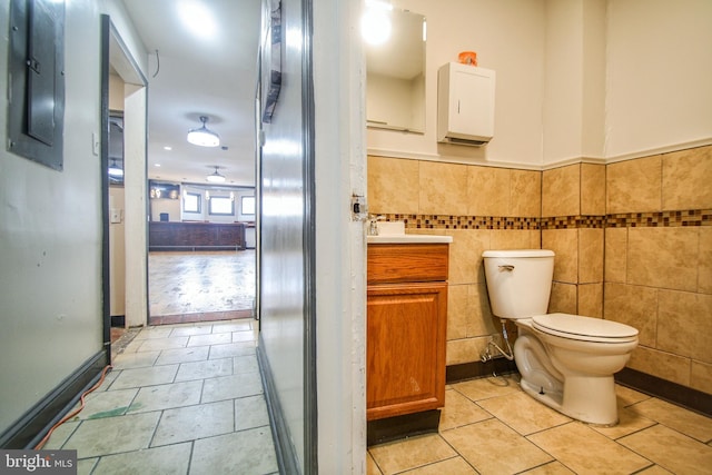 bathroom featuring tile patterned flooring, vanity, toilet, and tile walls