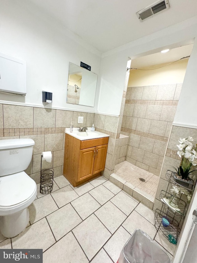 bathroom featuring vanity, tile walls, and toilet