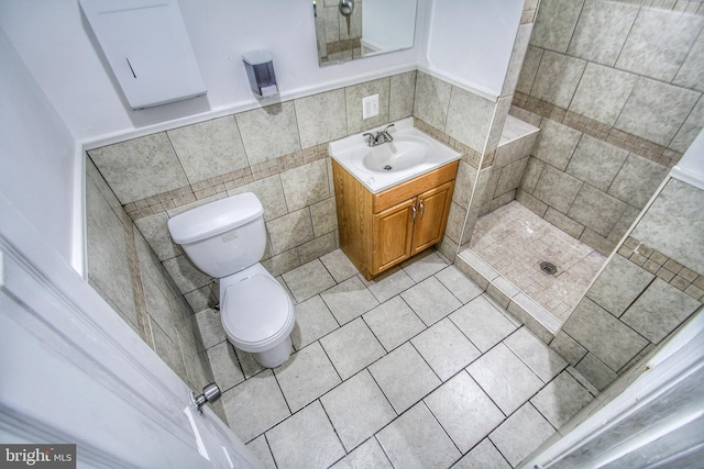 bathroom featuring walk in shower, tile patterned floors, toilet, vanity, and tile walls