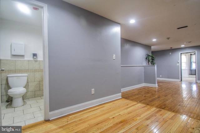 unfurnished room with tile walls and light wood-type flooring